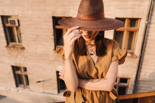 Jeune fille de la mode vêtue d'une robe d'été avec un chapeau large en osier marche et pose dans la vieille ville — Photo