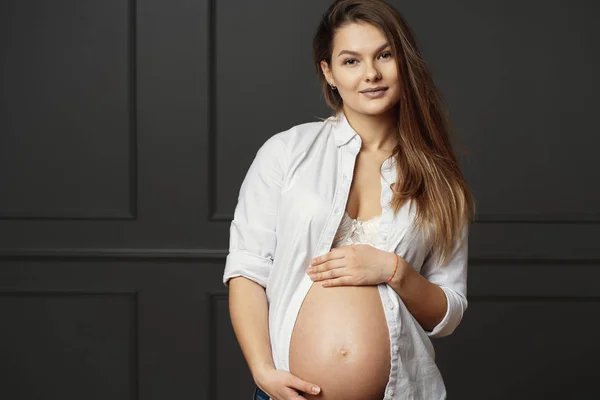 Krásná mladá těhotná žena se jemně dotýkala svého břicha a posílá lásku k jejímu nenarozené dítěti — Stock fotografie