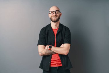 Sakallı ve gözlüklü gülümseyen genç bir adam.