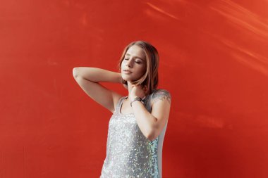 Kırmızı bir duvarın önünde poz neşeli genç kız