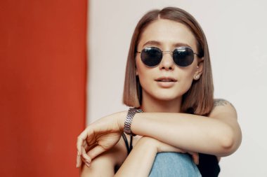 Kırmızı duvarın yanındaki beyaz sandalyede oturan genç kız