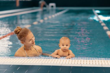 Anne ve küçük oğlu yüzme havuzunda eğleniyor.