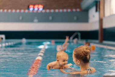 Anne ve küçük oğlu yüzme havuzunda eğleniyor.