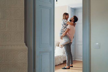 Yatak odalarında dururken sarılan sevgi dolu genç çiftin profil görünümü