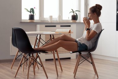 Şirin kız kahve içiyor ve kitap okuyor.