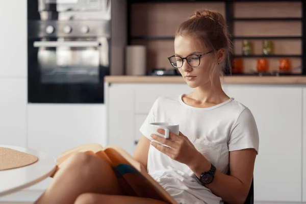 Linda chica está bebiendo café y leyendo un libro — Foto de Stock