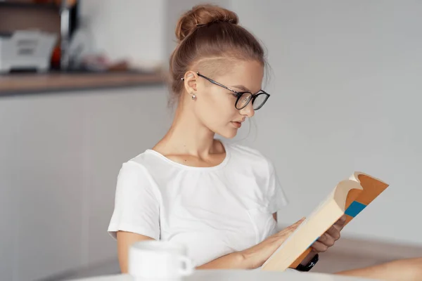 Söt flicka dricker kaffe och läser en bok — Stockfoto