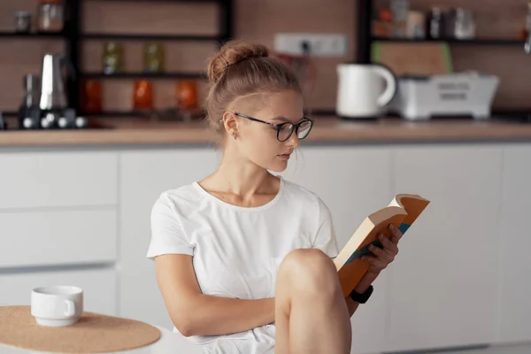Милая девушка пьет кофе и читает книгу. — стоковое фото