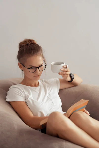 Linda chica está bebiendo café y leyendo un libro — Foto de Stock