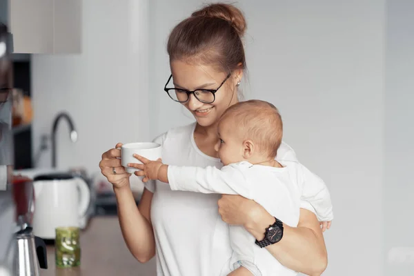 Mladá matka s dítětem v kuchyni — Stock fotografie