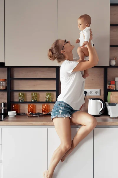 Junge Mutter mit Baby in der Küche — Stockfoto