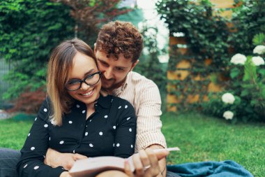 Aşık bir çift evinin bahçesinde çimenlerin üzerinde yatıyor. Kitap okuyan kız