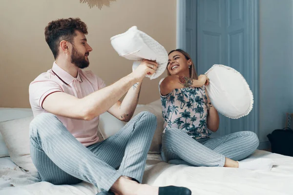 Couple in love on the bed. Pillow fight. Young happy couple beat the pillows on the bed in a bedroom at home.