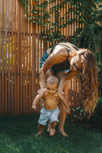 Chlapeček Bere První Krůčky Pomocí Mamky Zelené Trávě Dvorku — Stock fotografie