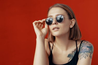 Kırmızı duvarın yanındaki beyaz sandalyede oturan genç kız. Pencereden gelen doğal ışık