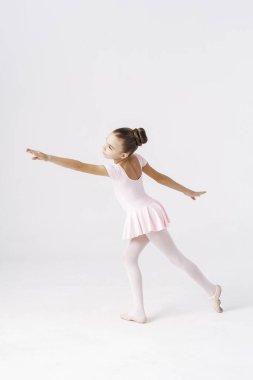 Stüdyoda beyaz arka planda bale pozu veren narin bir kız balerin. Kişilik gelişimi kavramı.