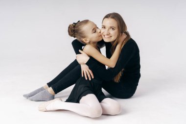 Mother encourages her daughter ballerina sitting on the floor on white background. clipart