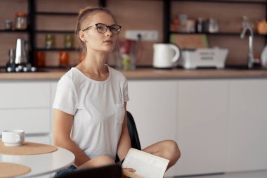 Şirin kız kahve içiyor ve kitap okuyor.