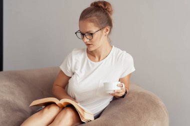 Şirin kız kahve içiyor ve kitap okuyor.