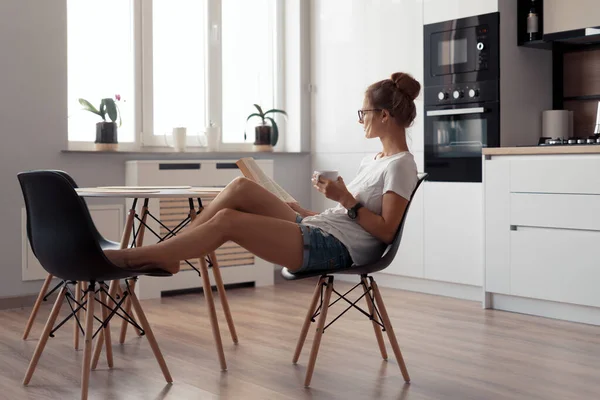 Ragazza carina sta bevendo caffè e leggendo un libro — Foto Stock