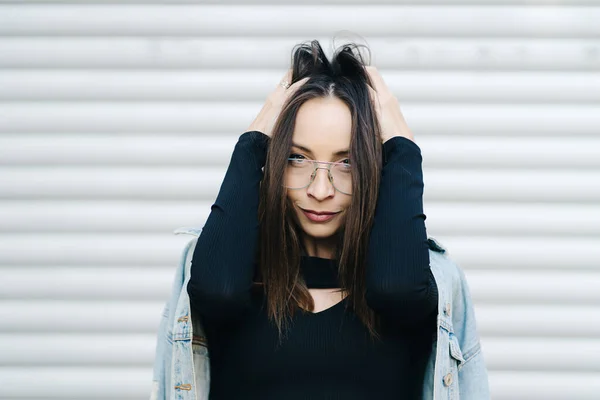 Retrato de mujer joven con gafas. Mujer de estilo bonito con el pelo largo y oscuro con una chaqueta de mezclilla —  Fotos de Stock