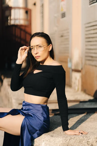 Atractiva joven morena con un top negro y gafas transparentes posando en la calle — Foto de Stock