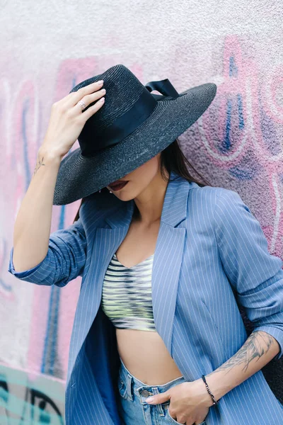 Retrato de moda de una joven vestida con una chaqueta de rayas azules y un sombrero negro — Foto de Stock