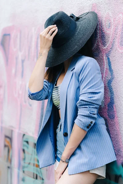 Retrato de moda de uma jovem vestida com uma jaqueta listrada azul e chapéu preto — Fotografia de Stock