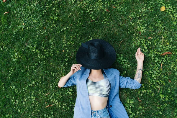 Retrato de moda de una joven vestida con una chaqueta de rayas azules y un sombrero negro — Foto de Stock