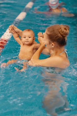 Anne ve küçük oğlu yüzme havuzunda eğleniyor.