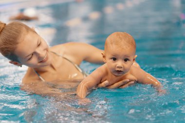 Anne ve küçük oğlu yüzme havuzunda eğleniyor.