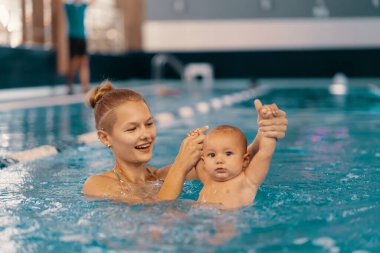 Anne ve küçük oğlu yüzme havuzunda eğleniyor.