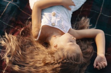 Doğada battaniyeye uzanmış sevimli küçük bir kız.