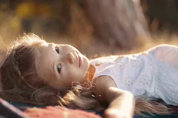 Charmant klein meisje liggend op een deken in de natuur — Stockfoto