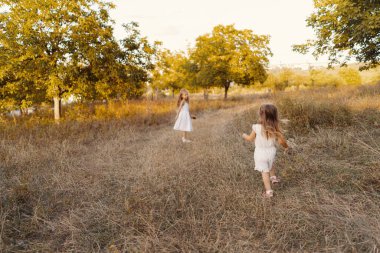 Güzel kız kardeşler doğada tatil yaparken oyun oynuyorlar.