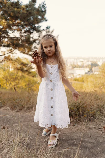 Gadis kecil dengan rambut bergelombang bermain sambil beristirahat di alam — Stok Foto