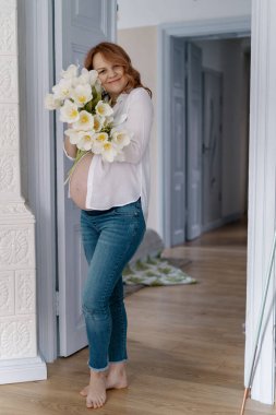 Evde beyaz laleli hamile bir kadın var.