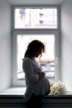 Evde beyaz laleli hamile bir kadın var.