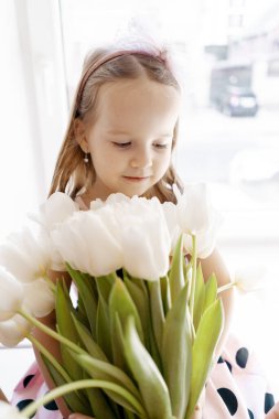 Pencerenin yanında beyaz laleli küçük kız
