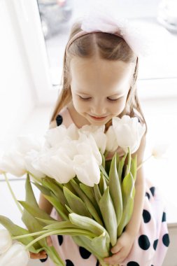 Pencerenin yanında beyaz laleli küçük kız