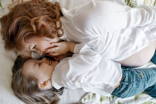 Těhotná matka a dcera ležící na posteli — Stock fotografie