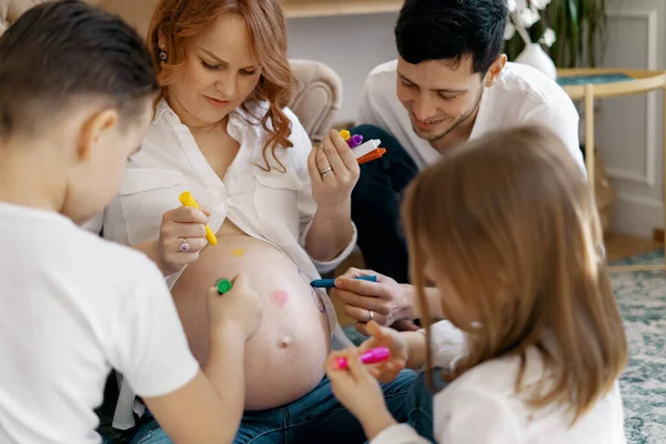 Glückliche Familie zeichnet Herzen auf Mamas Bauch — Stockfoto