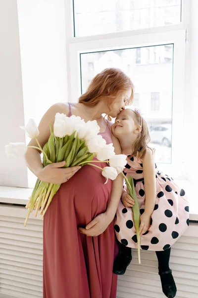 Retrato madre embarazada con su hija y tulipanes blancos —  Fotos de Stock