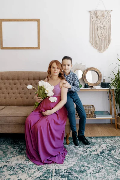 Portrét těhotné matky se svým synem na pohovce — Stock fotografie