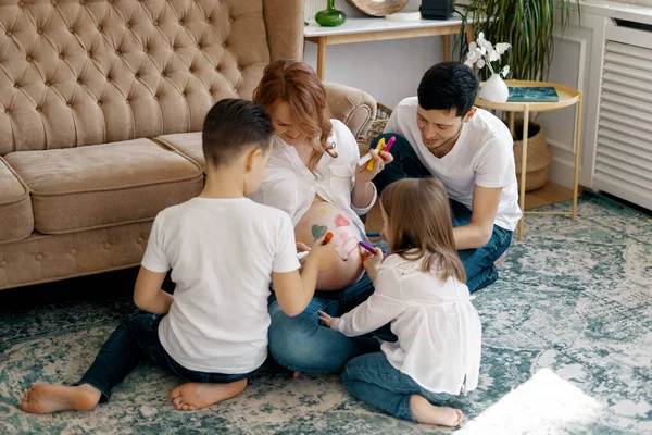 Glückliche Familie zeichnet Herzen auf Mamas Bauch — Stockfoto