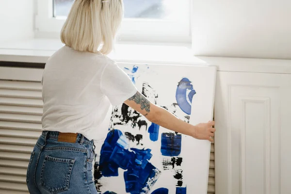 Jovem mulher colocando tinta abstrata na parede — Fotografia de Stock