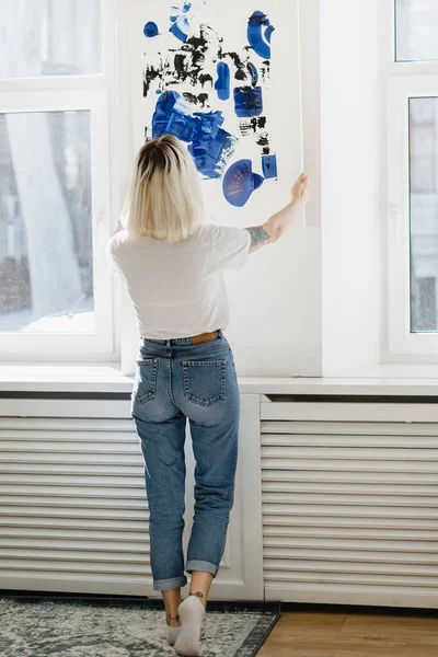 Jonge vrouw plaatst abstracte verf op de muur — Stockfoto