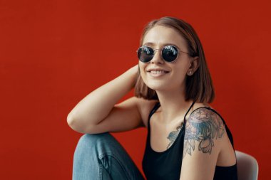 Kırmızı duvarın yanındaki beyaz sandalyede oturan genç kız