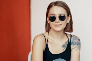 Kırmızı duvarın yanındaki beyaz sandalyede oturan genç kız