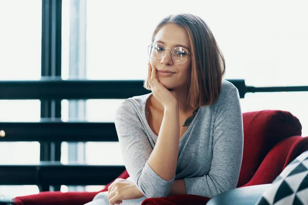 Attraktive Mädchen sitzt in einem roten gemütlichen Stuhl — Stockfoto